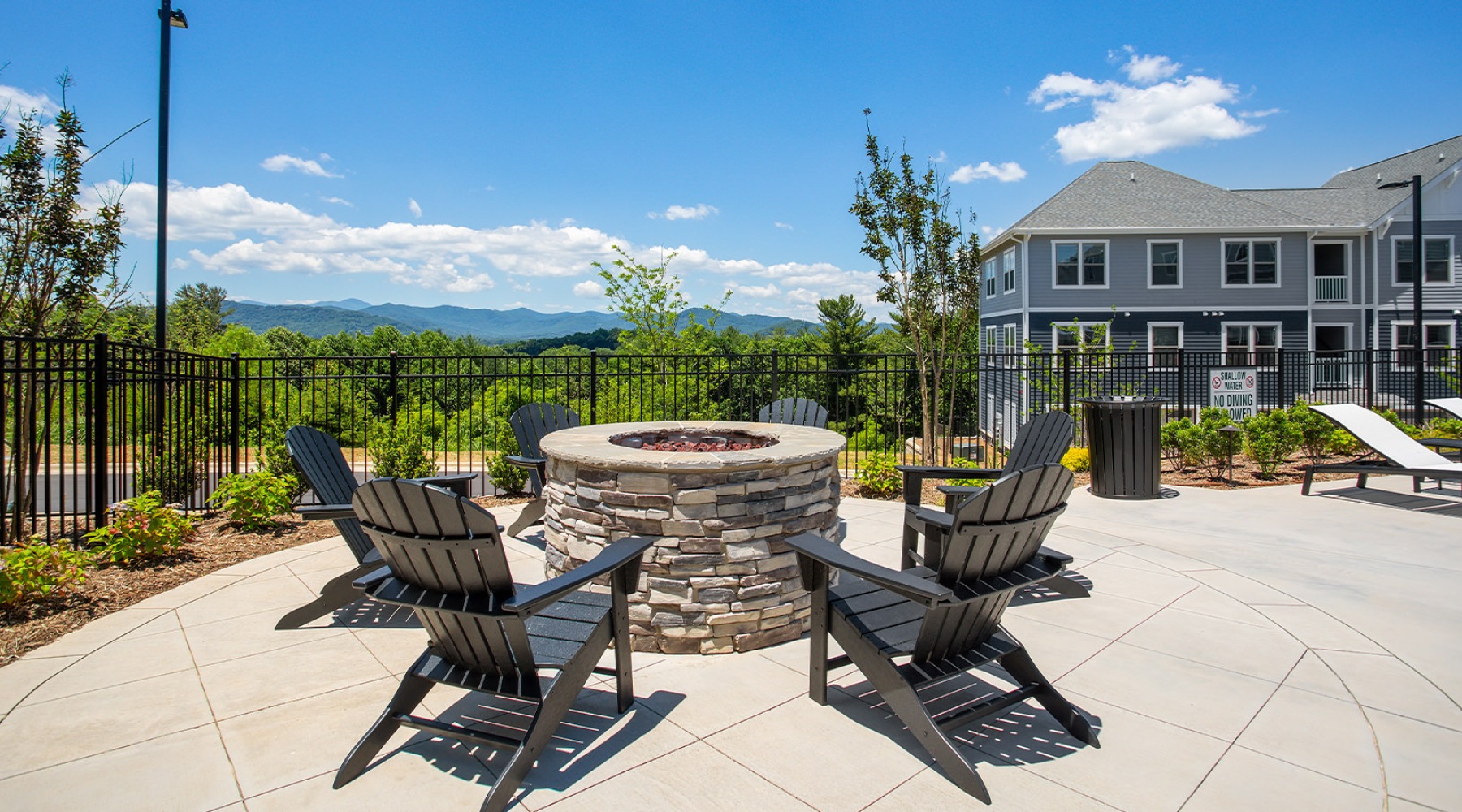 Beautiful fire pit with chairs situated on a deck that over looks the scenery at Burton Hills apartment community near Asheville in Arden North Carolina.