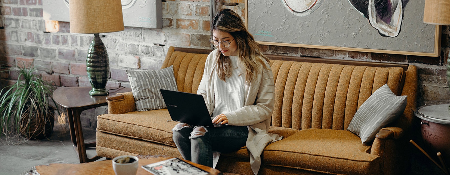 Woman on couch working on laptop